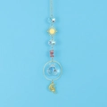 Detail of crystal suncatcher with moon fairy charm and faceted glass ball on blue sky - Watermelon red