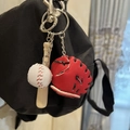 Baseball keychain set with wooden bat, white ball and red glove hanging on a black backpack - 2CM Long Bat White Ball Red Glove Black Strap
