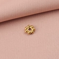 Detailaufnahme goldener Schneeflocken-Metallperlen auf weichem rosa Stoffhintergrund - 4mm / Gold