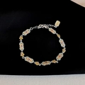 Close-up of enamel flower bracelet with silver chain and brand tag on black velvet - Green & Yellow