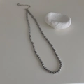 Dettaglio collana di perle grigio scuro con catena regolabile su una pietra bianca - Collana di perle da 4mm