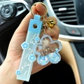 Hand holding light blue sakura quicksand keychain with acrylic flower and oil glitter effect - Light Blue