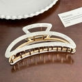 Chic marble white acetate hair claw clip with golden metal teeth on dark wood surface - Curved Crescent Claw