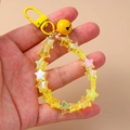 Macro view of a yellow star beaded wrist strap keychain with a matching metal bell charm - Yellow