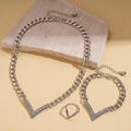 Detail van zilveren V-vormige sieradenset met ketting, armband en ring op decoratieve steen - 3-delige set / Zilver