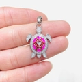 Pendentif tortue en argent avec émail rose et cristaux de zircon tenu à la main - Argent Émail Rose