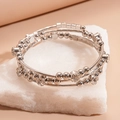 Nahaufnahme eines silbernen mehrlagigen Perlenarmbands mit Strass auf weißem Stein - Silber