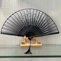 Elegant black folding fan with white floral patterns and hollowed-out bamboo ribs - Fragrance in the Cold