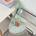 Close-up of minimalist mint green woven mesh tote bag hanging on a modern chair - Grey Green