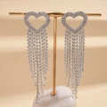 Primer plano de aretes de corazón plateados con borlas de pedrería en soporte dorado - Plateado