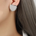 Minimalist silver heart stud earrings with a glossy finish shown on model's ear - Large (F1072) / Silver