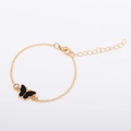 Detail of adjustable gold chain bracelet featuring a black butterfly charm and lobster clasp - Black