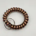 Macro detail of bronze matte spiral plastic wrist keychain with silver metal ring - Metallic Dark Coffee
