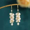 Detalle macro de pendientes dorados con racimo de perlas blancas en forma de gota - Racimo de Perlas Doradas