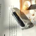 Essential oil roller bottle with natural black obsidian chips and a light wood cap - Obsidian