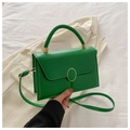 Détail du sac bandoulière en cuir PU vert avec boucle dorée sur literie blanche - Vert