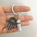 Detail of Hamsa Hand pendant with white turquoise hexagonal crystal on silver keychain - Howlite
