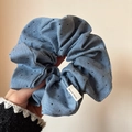 Scrunchie blu fatto a mano con pois neri ed etichetta tessuta mostrato sulla mano - Blu