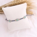 Detail of bohemian woven bead bracelet with turquoise accents and gold beads on soft pillow - Gray