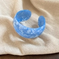 Detail van een brede acryl manchetarmband met blauwe marmertextuur op linnen - Blauw