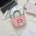 Detailed view of pink heart quilted mini bag with blue denim strap on desk - Pink