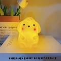 Cute cartoon animal night light in warm yellow glow placed on a book home decor - Pompompurin