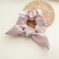 Detailed macro of pink-purple bow hair scrunchie with crinkle silk texture on rattan mat - Korean Pink