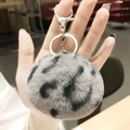 Gray leopard print plush ball keychain with silver heart clasp on hand-held closeup - Grey Leopard Pom Pom