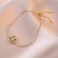 Golden rotating clover charm bracelet with green and white zircons on beige silk - Emerald Heart Bracelet / Gold