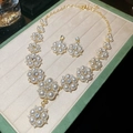 Vista de cerca del conjunto de joyas de flores doradas con perlas blancas y cristales - Conjunto de Perlas Blancas de Metal Dorado