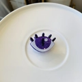 Macro shot of purple glitter eyeball hair clip with black eyelashes on a white ceramic plate - Mini Purple Devil Eye