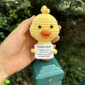 Handgefertigte gelbe Häkelente mit einer inspirierenden weißen Grußkarte in der Hand - Gelbe Ente
