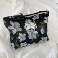 Dettaglio della trama jacquard floreale e dell'etichetta in tessuto della borsa a spalla - Borsa cosmetica in jacquard nera con motivo floreale bianco