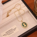 Detailed shot of vintage portrait pendant with green enamel and pearls in a jewelry box - Blue Green