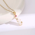 Macro shot of gold-plated pendant with white resin, red zircon, and leaf motifs - Golden White Bamboo