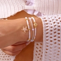 Close-up of bohemian layered bracelets with gold starfish, seashell charms and white beads - Starfish Multi-layer Bracelet (BR25Y0185)
