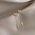 Macro shot of gold heart-shaped tassel earrings with pavé crystals on grey silk - Gold ED68067 Long Heart Tassel