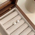 Primer plano de aretes de perlas blancas minimalistas en un joyero de madera y lino vintage - 8mm