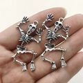 Pair of dancing silver skeleton pendants for Halloween DIY jewelry making on a hand - Silver
