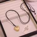 Long collier pull tendance avec pendentif cœur en or mat et cordon noir sur plateau bijoux - Doré