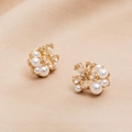 Macro view of gold flower earrings with zircon crystals and pearls on beige fabric - Flower Crystal Pearl Stud (ER21Y0628)