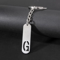 Polished stainless steel keychain with cutout letter G on a black display stand - Letter G
