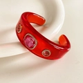 Close-up of a vintage red resin bangle featuring pink rhinestones on a white plate - Red Base with Rose Red Zirconia