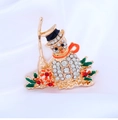 Close-up of golden snowman brooch with sparkling rhinestones and colorful enamel details - White K Orange Snowman (BR1402)