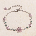 Close-up of pink zircon flowers and green marquise gems on a silver chain bracelet - Platinum - Single Prong