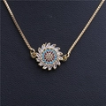 Macro shot of gold-plated sunburst pendant with zircon stones and blue-red gem details - Sunflower Round Necklace