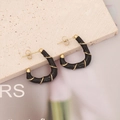 Fashionable C-shaped black enamel earrings with gold wire detail on stone surface - Black