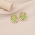 Close-up of vintage gold earrings with white pearl border and green rose relief - Green