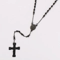 Detalle de collar de cuentas negras con un colgante de cruz minimalista de acero - Negro