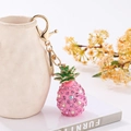 Dettaglio portachiavi ananas con cristalli rosa e chiusura dorata su vaso bianco - Portachiavi / Rosa
